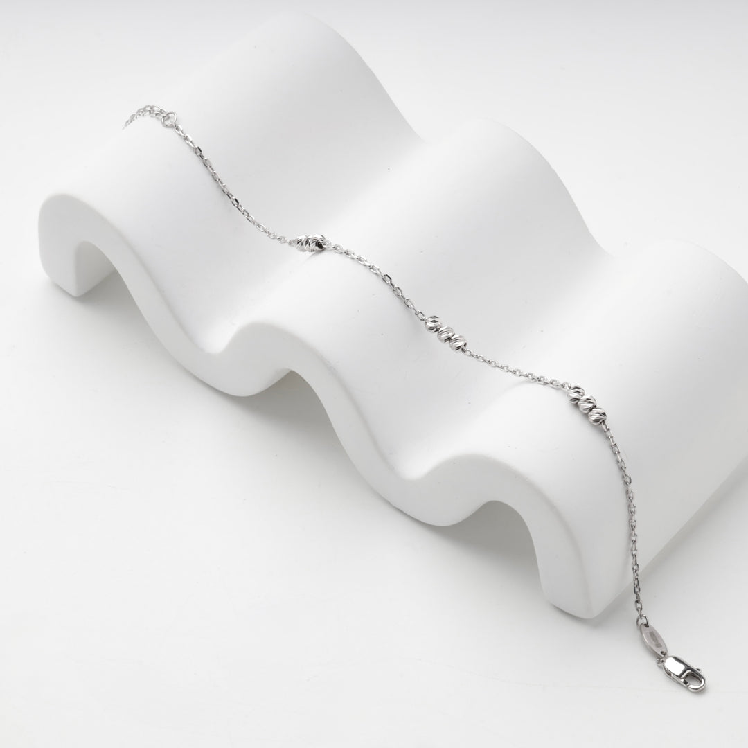 Silver 925 bracelet draped over a white wave-shaped display block