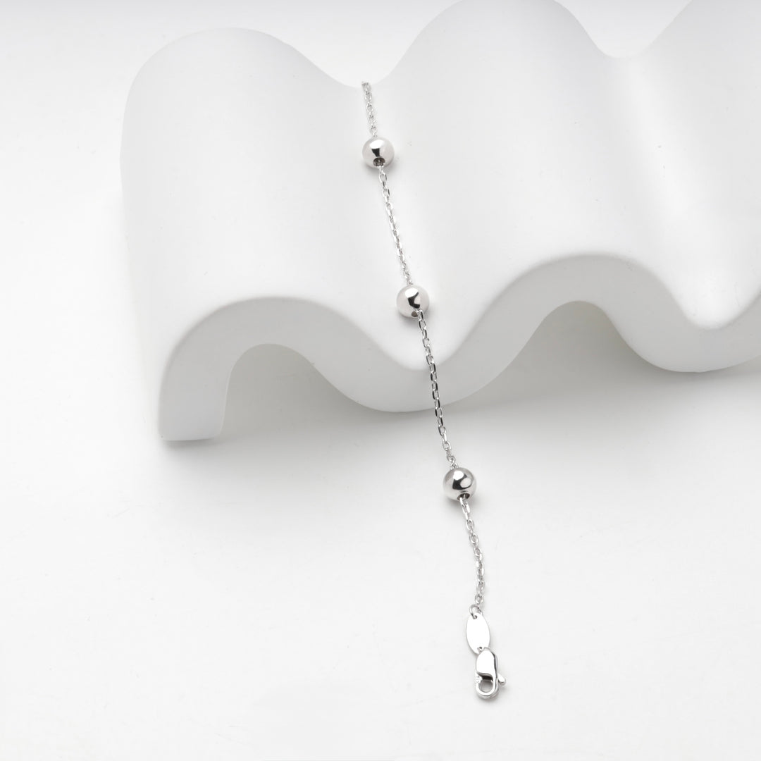 Silver 925 ball bracelet draped over a white display prop