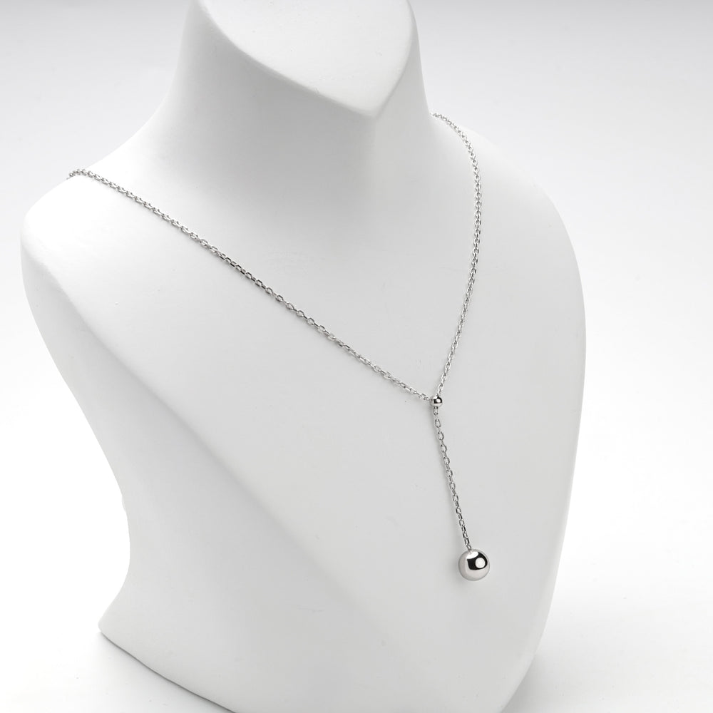 Necklace worn long, the ball drop hanging low on the neckline