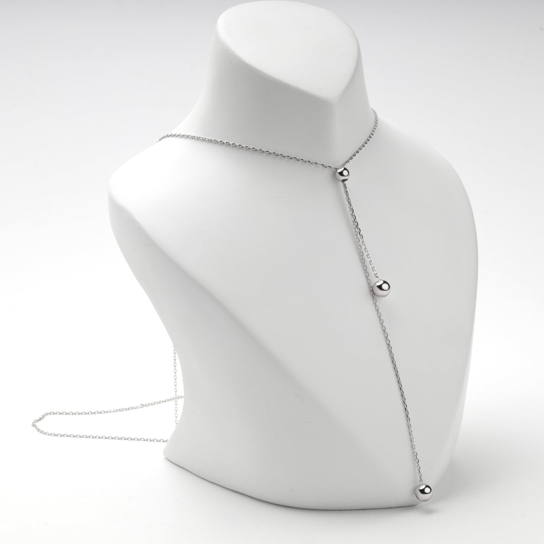 Silver bolo necklace on a white bust with the tails hanging to one side