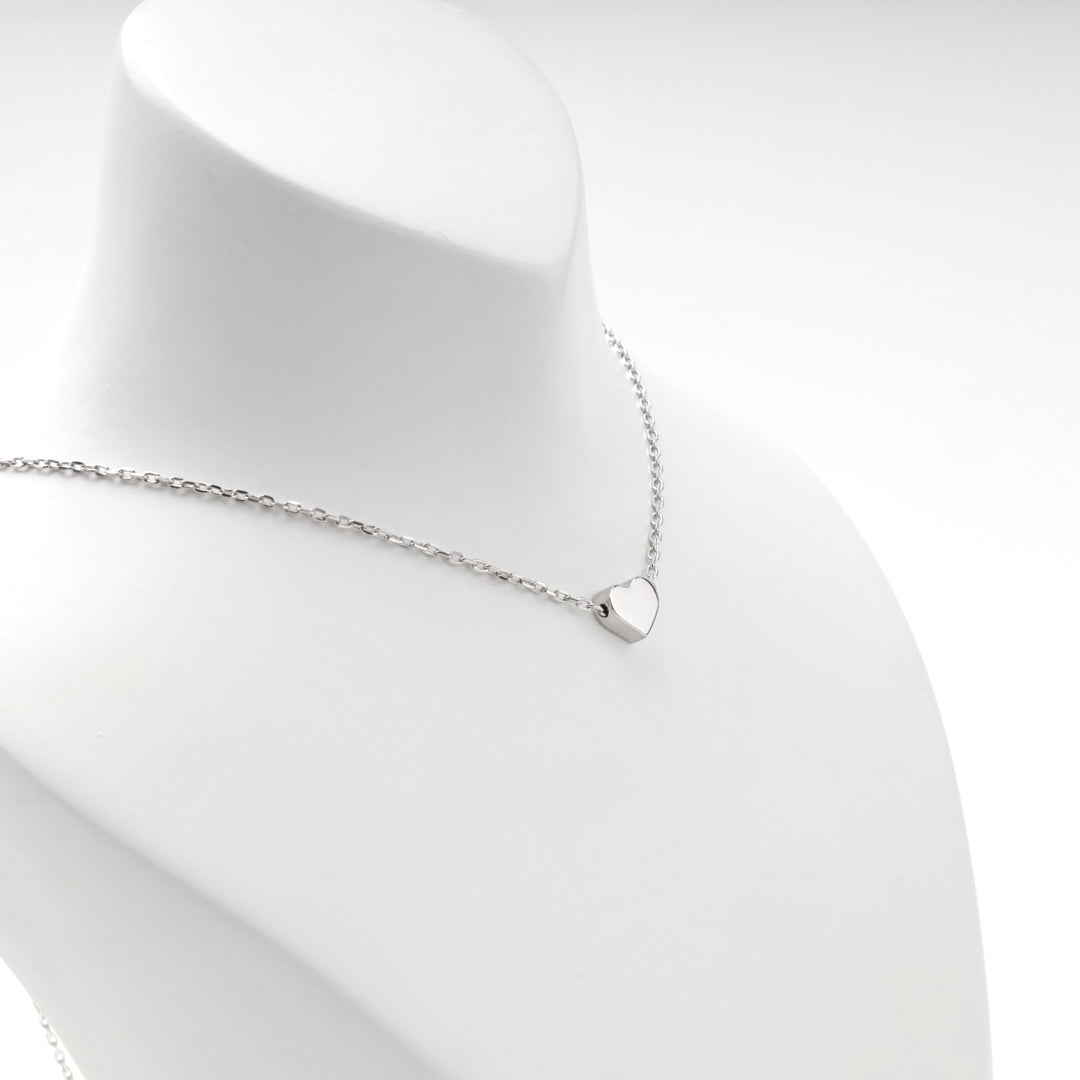 Silver heart necklace worn short, angled view