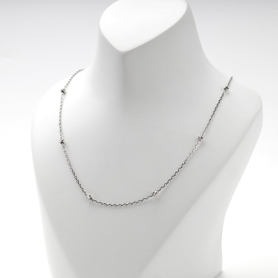 Faceted silver beads spaced along the anchor chain of the necklace