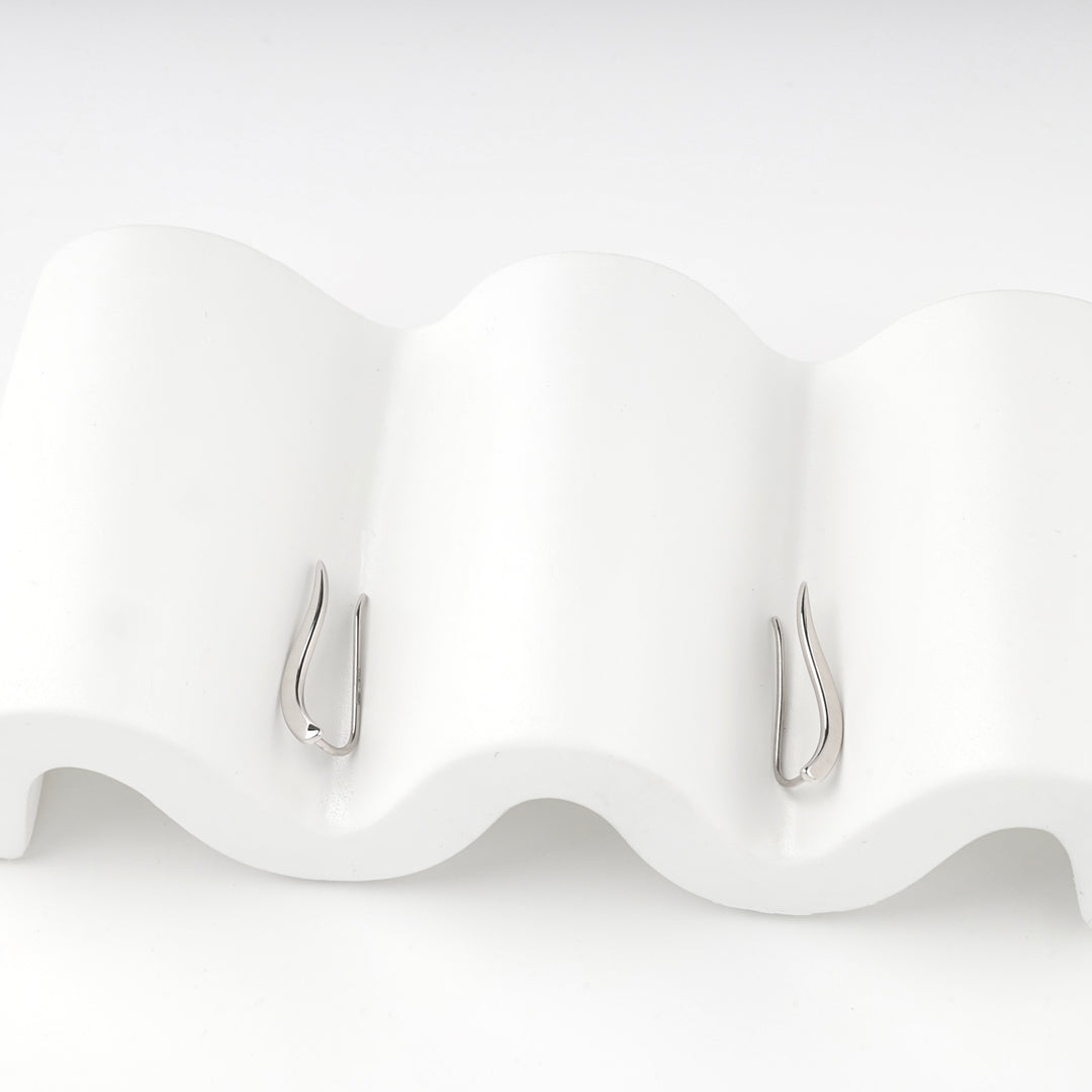 Silver 925 curved bar climber earrings hooked over a white wave stand