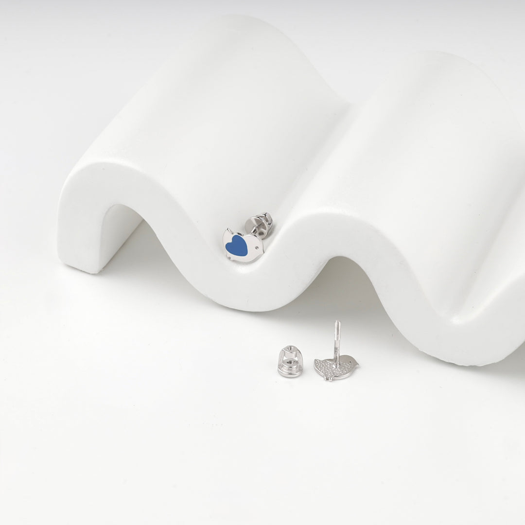 Blue enamel bird stud earring on a white wave display with the second earring beside it