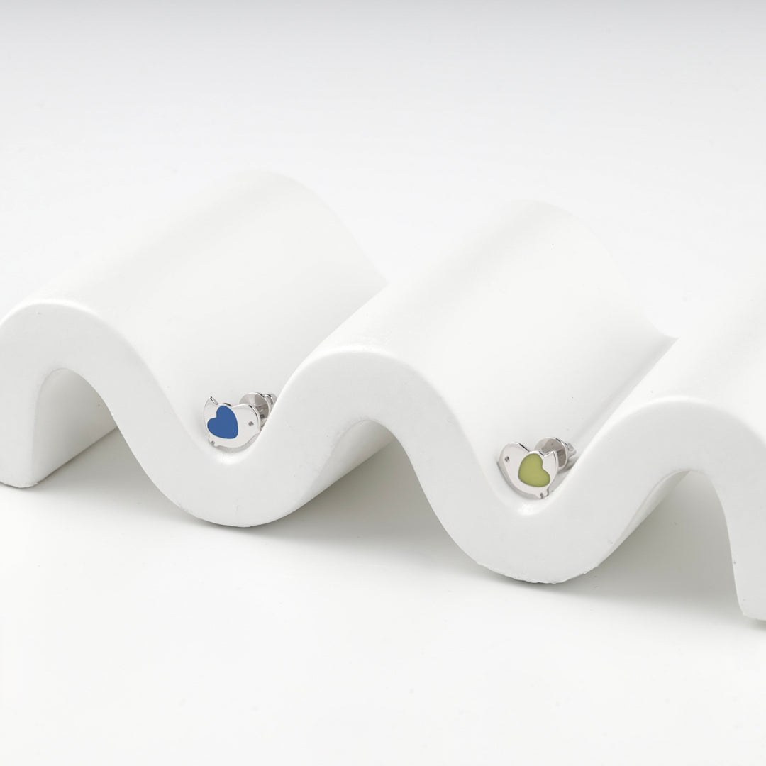 Blue and yellow enamel bird stud earrings resting on a white wave display