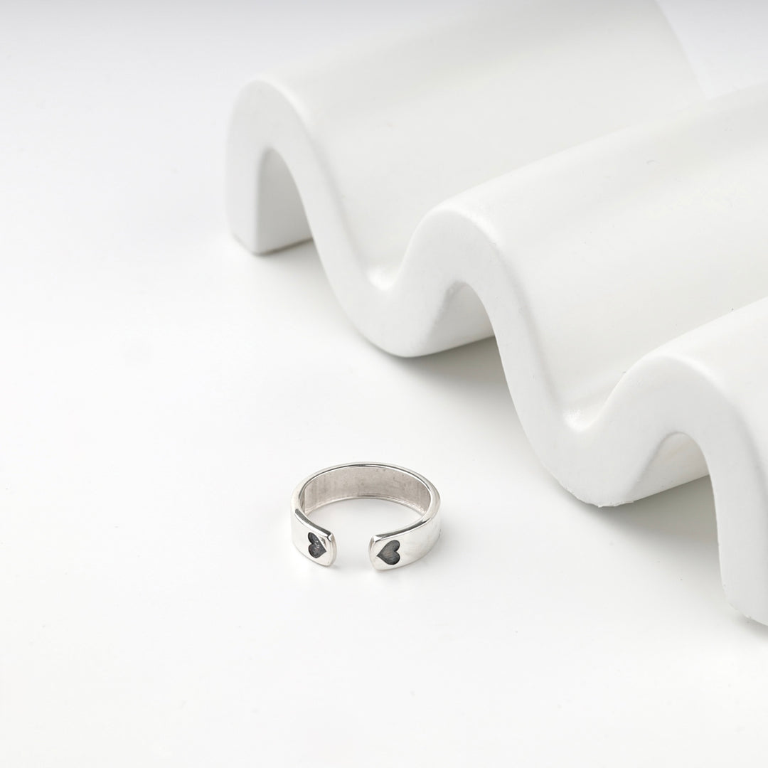 Open silver ring showing the two blackened hearts at the ends of the band