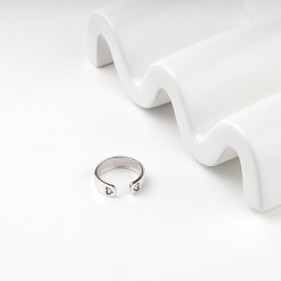 Silver 925 open ring showing the two blackened hearts beside a white display