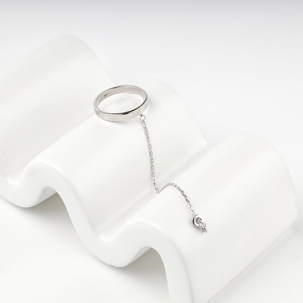 Silver 925 chain ring resting on a white wave-shaped display block