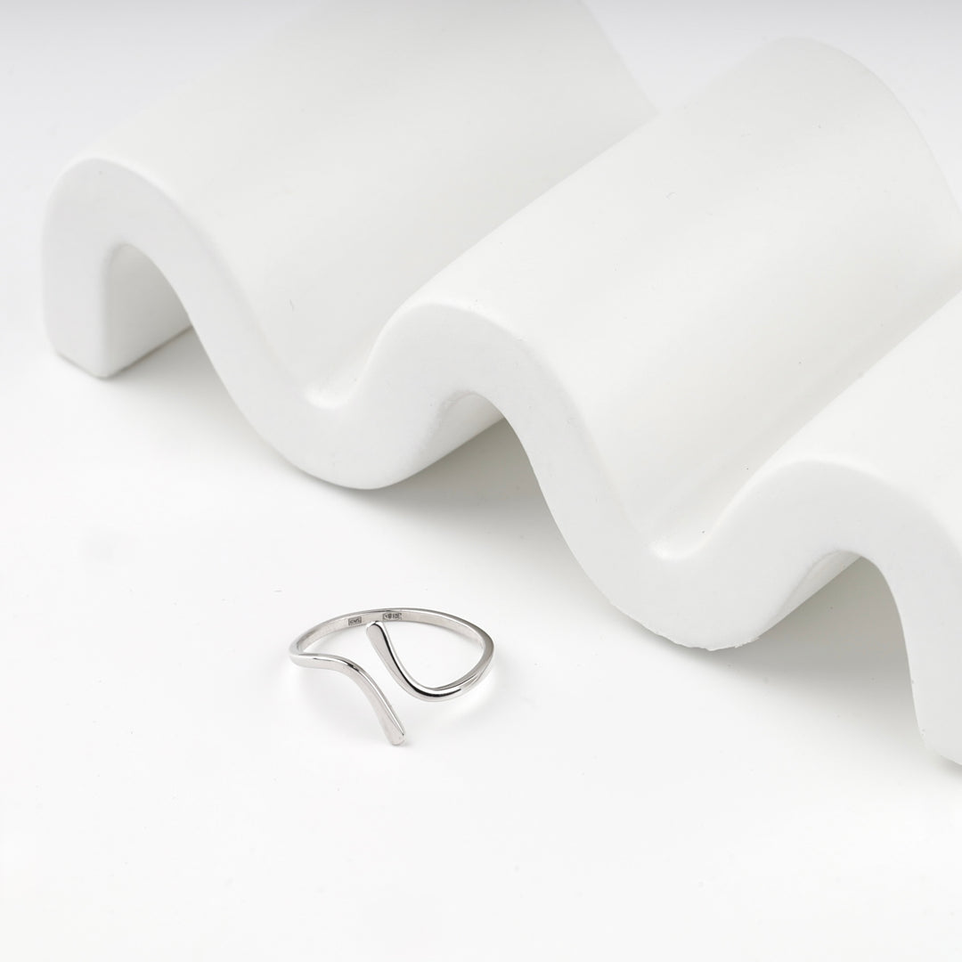Silver 925 open wave ring beside a white wave-shaped display block