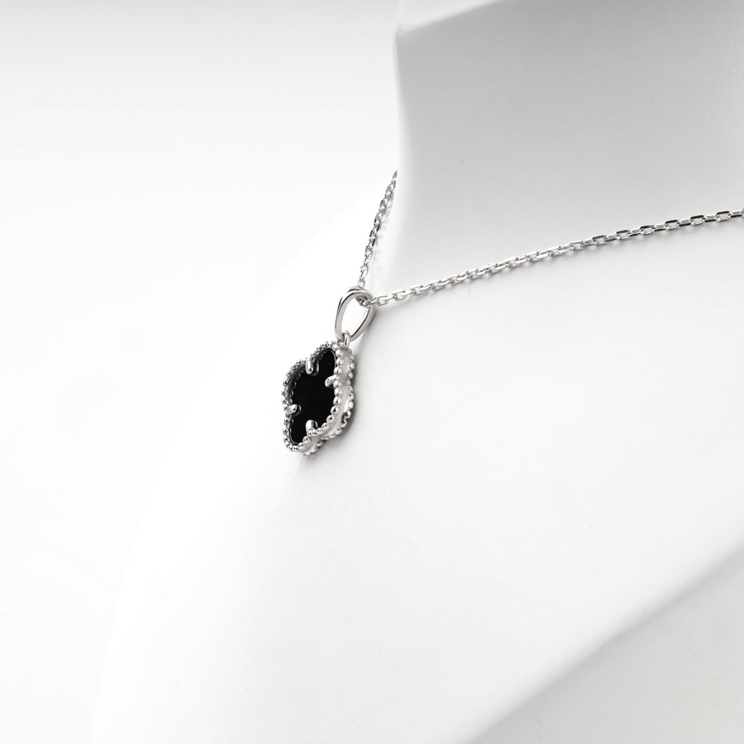Close view of the black onyx clover pendant and the anchor-link silver chain