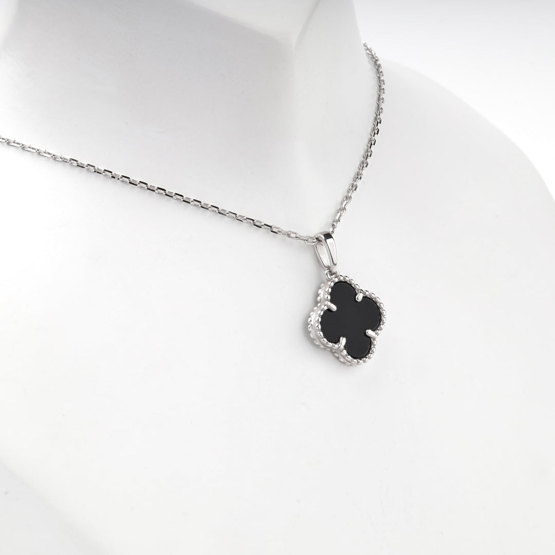 Black onyx clover pendant with a beaded silver frame and bail, angled close view