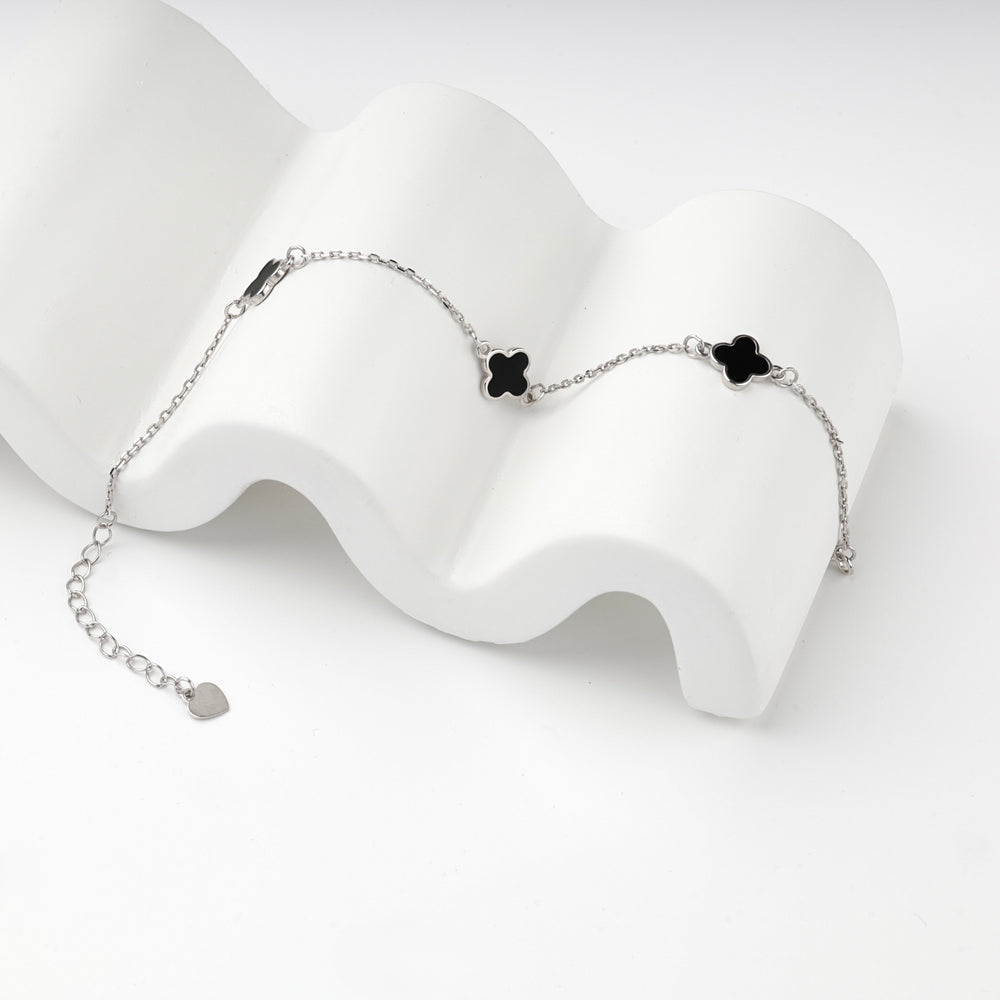 Close view of the black clovers and silver 925 chain on a white prop