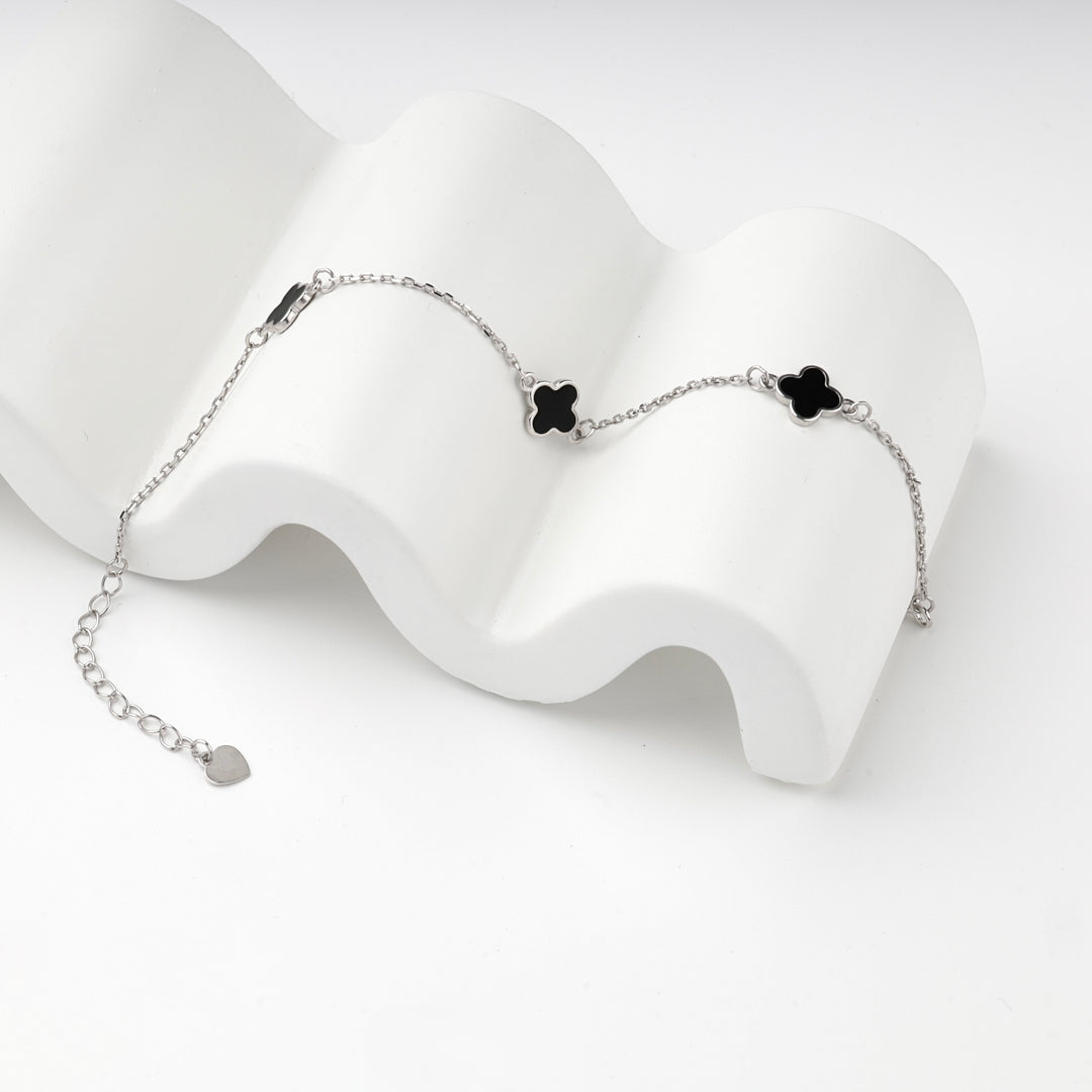 Close view of the black clovers and silver 925 chain on a white prop