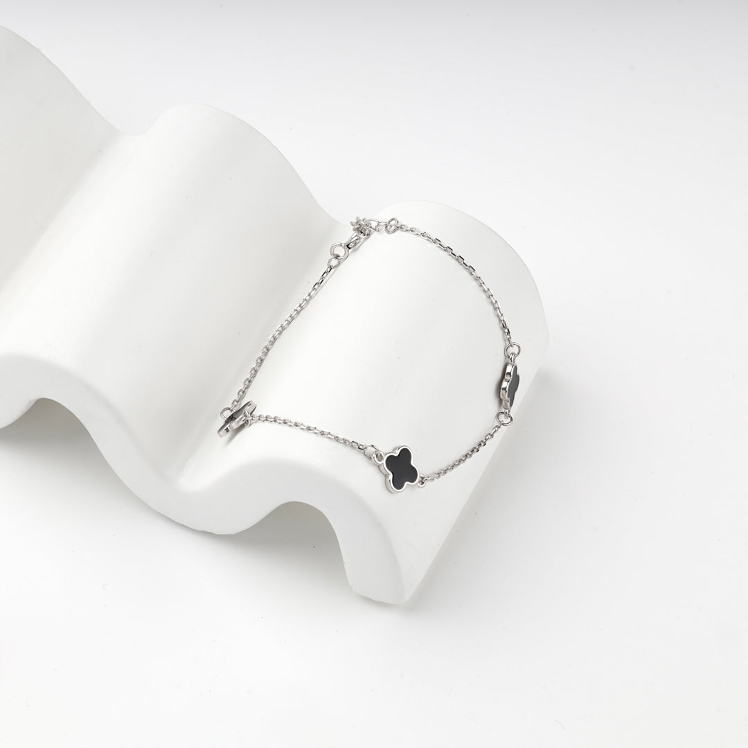 Silver 925 black clover bracelet arranged on a white display block