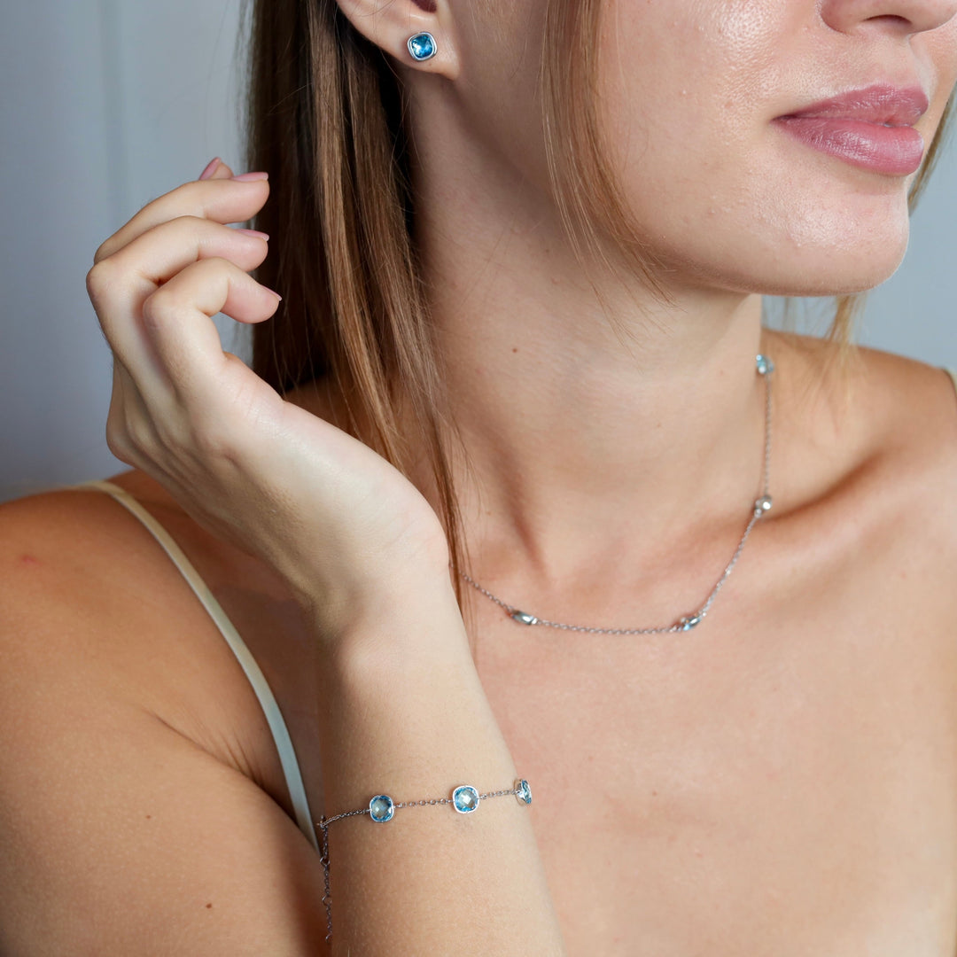 Close-up of a woman wearing a silver necklace with blue stones against a neutral background