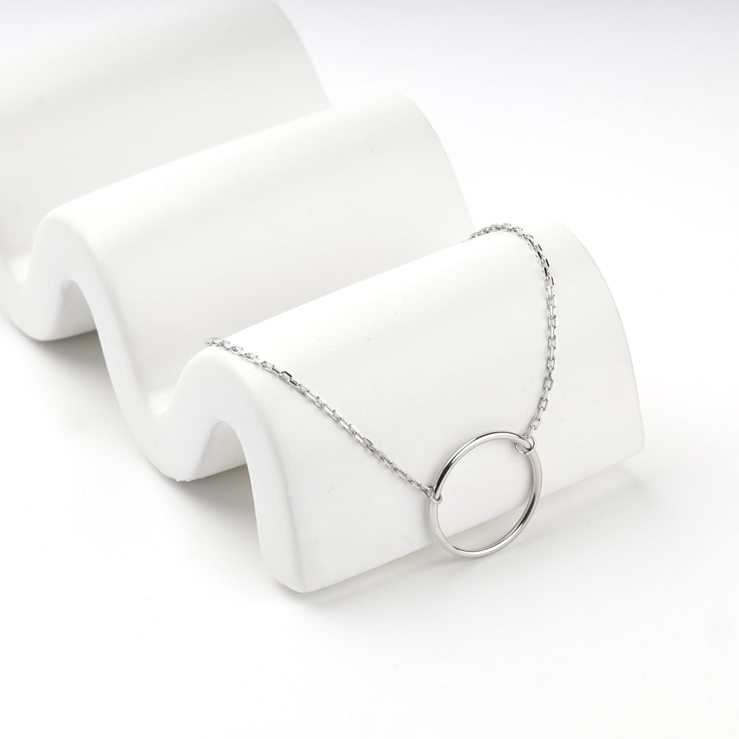 Silver 925 circle bracelet draped over a white wave-shaped display block