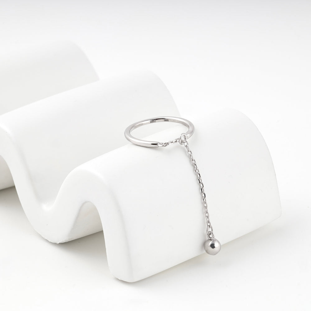 Ring with chain drop resting on a white wave display
