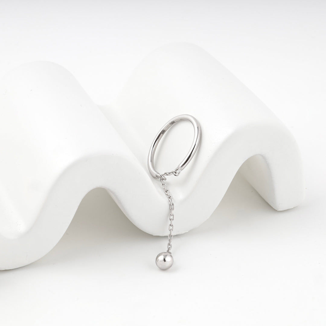 Angled view of the silver ring and its ball drop on a white display