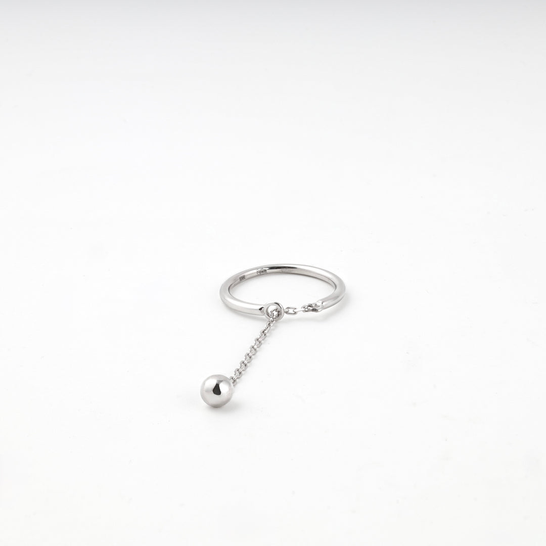Silver ring lying flat with the chain and polished ball
