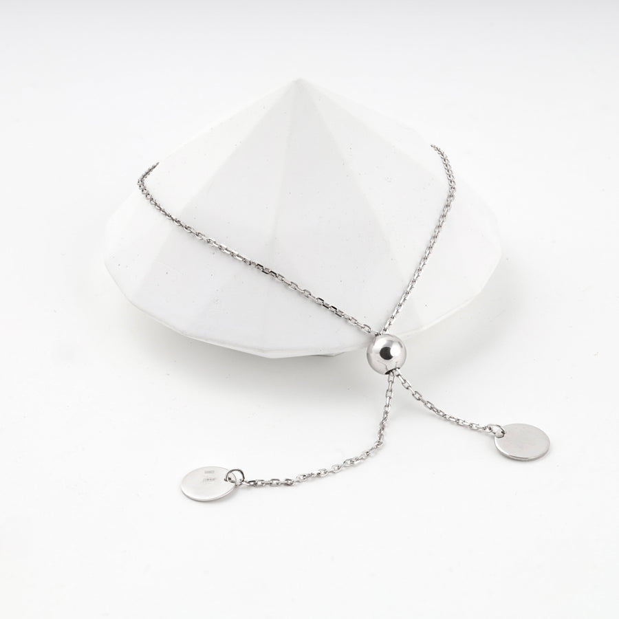 Silver 925 adjustable bracelet with two disc charms on a white faceted prop