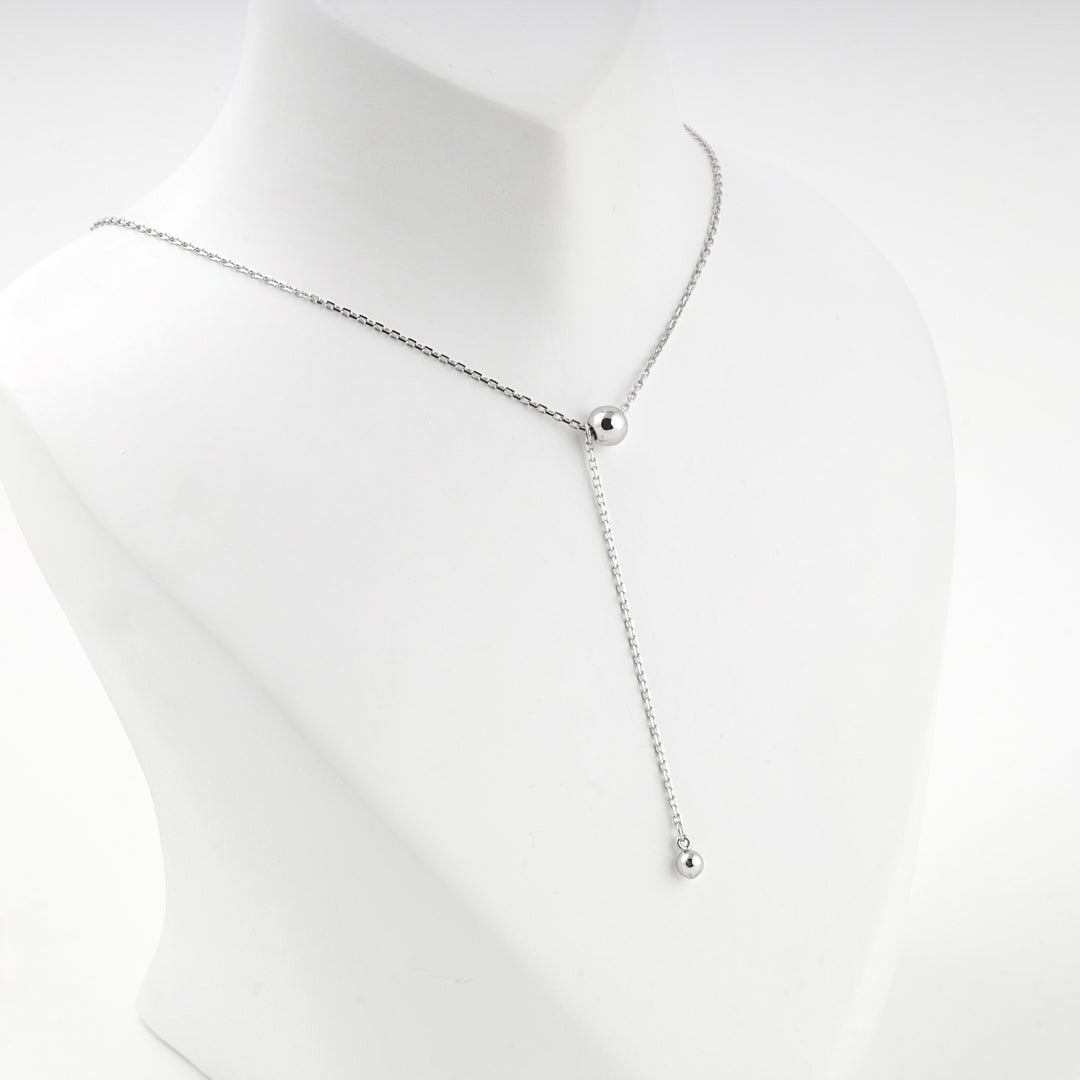 Ball drop Y necklace worn at the base of the neck, front view