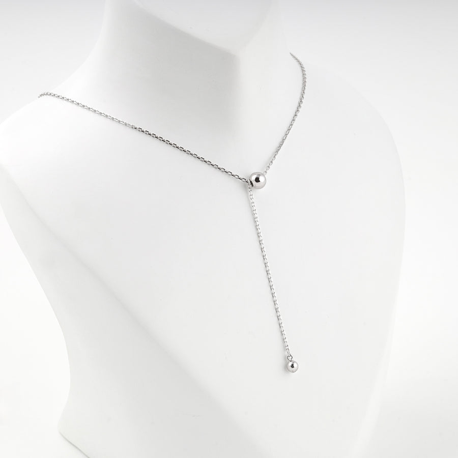 Ball drop Y necklace worn at the base of the neck, front view
