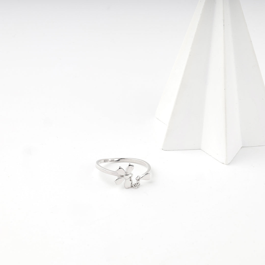 Silver flower ring beside a white display cone