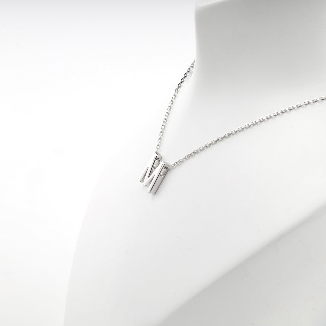 Angled view of the letter M pendant hanging from the chain