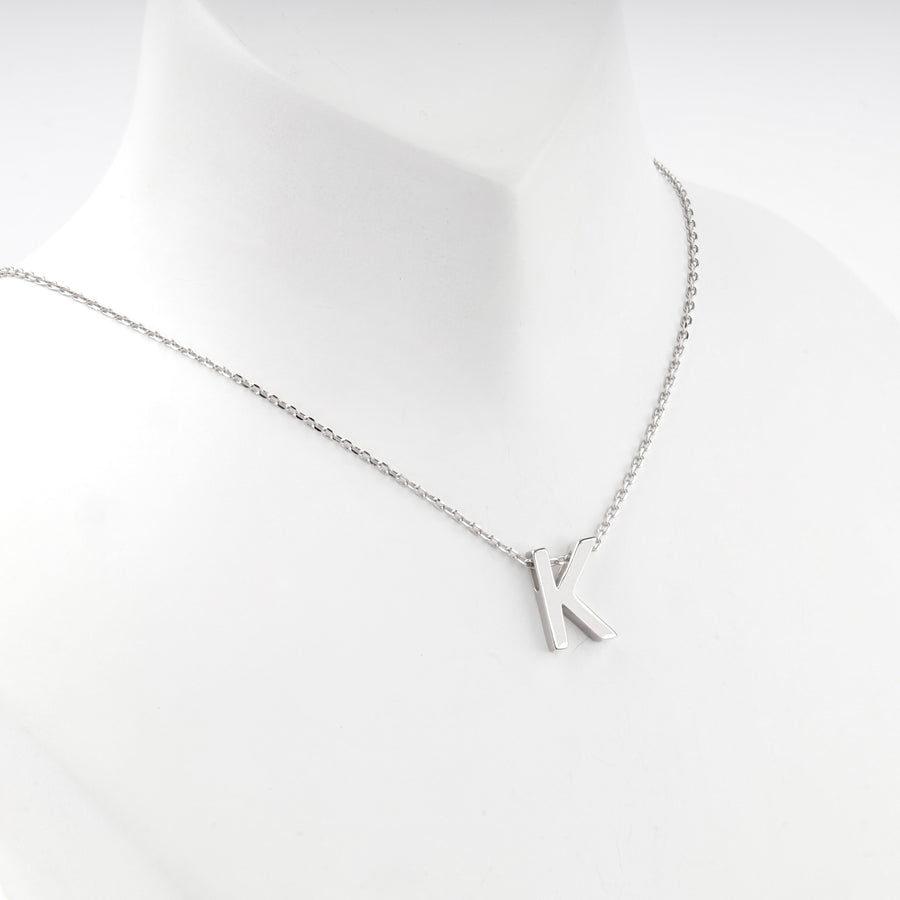 Letter K necklace worn at the base of the neck, front view