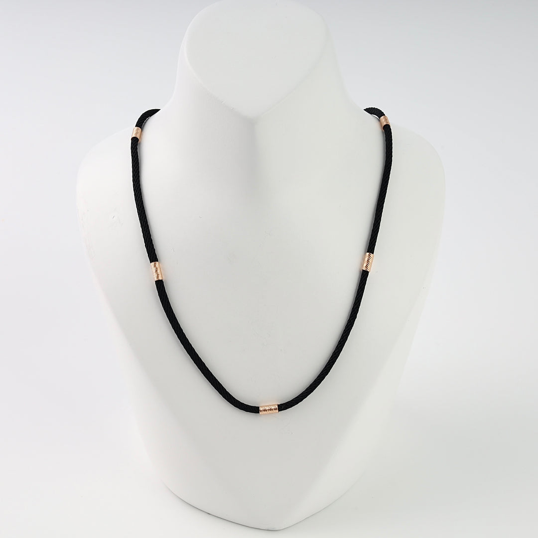 Black cord necklace with small gold tube beads on a display stand, minimalist Ukrainian Jewelry, black rope chain necklace.
