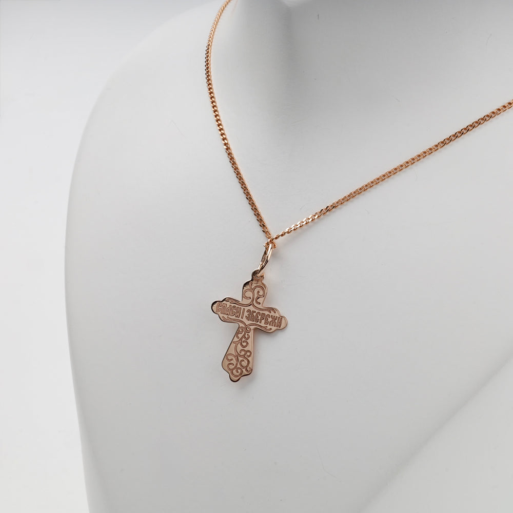 Rose gold cross pendant on a chain showing the Ukrainian Save and Protect engraving