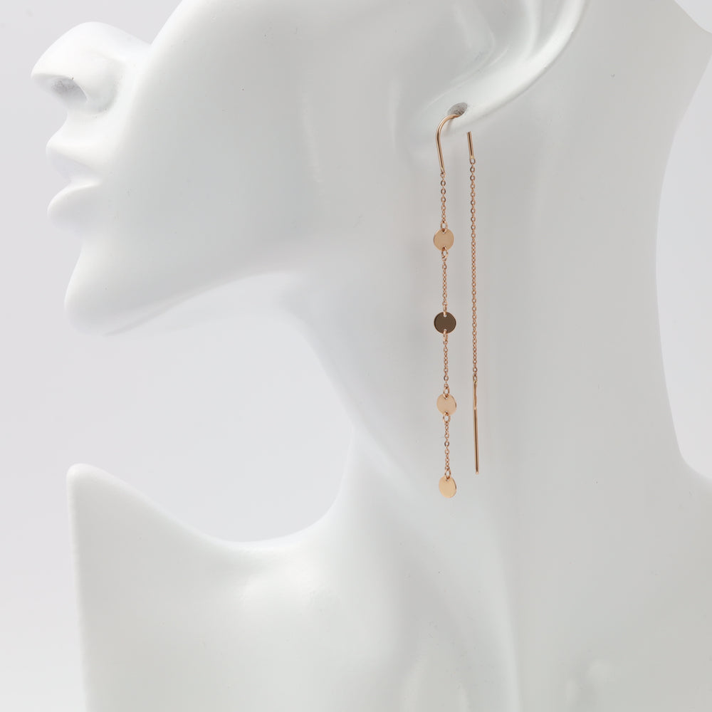 Rose gold threader earrings with flat disc charms worn on model