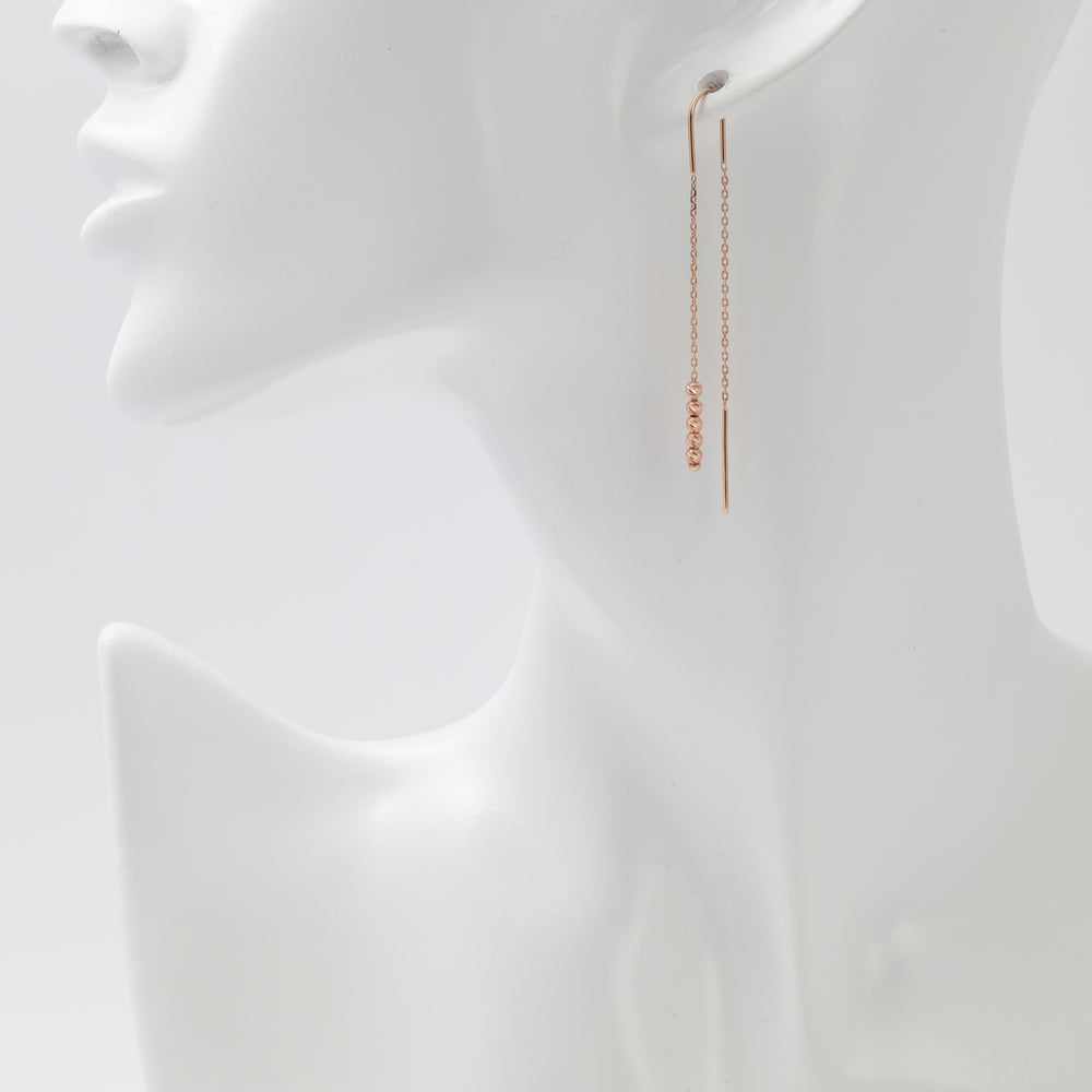 Rose gold threader earrings with faceted bead chain worn on model