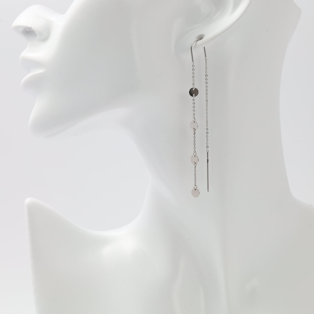 Gold chain earring on a mannequin ear with a plain background