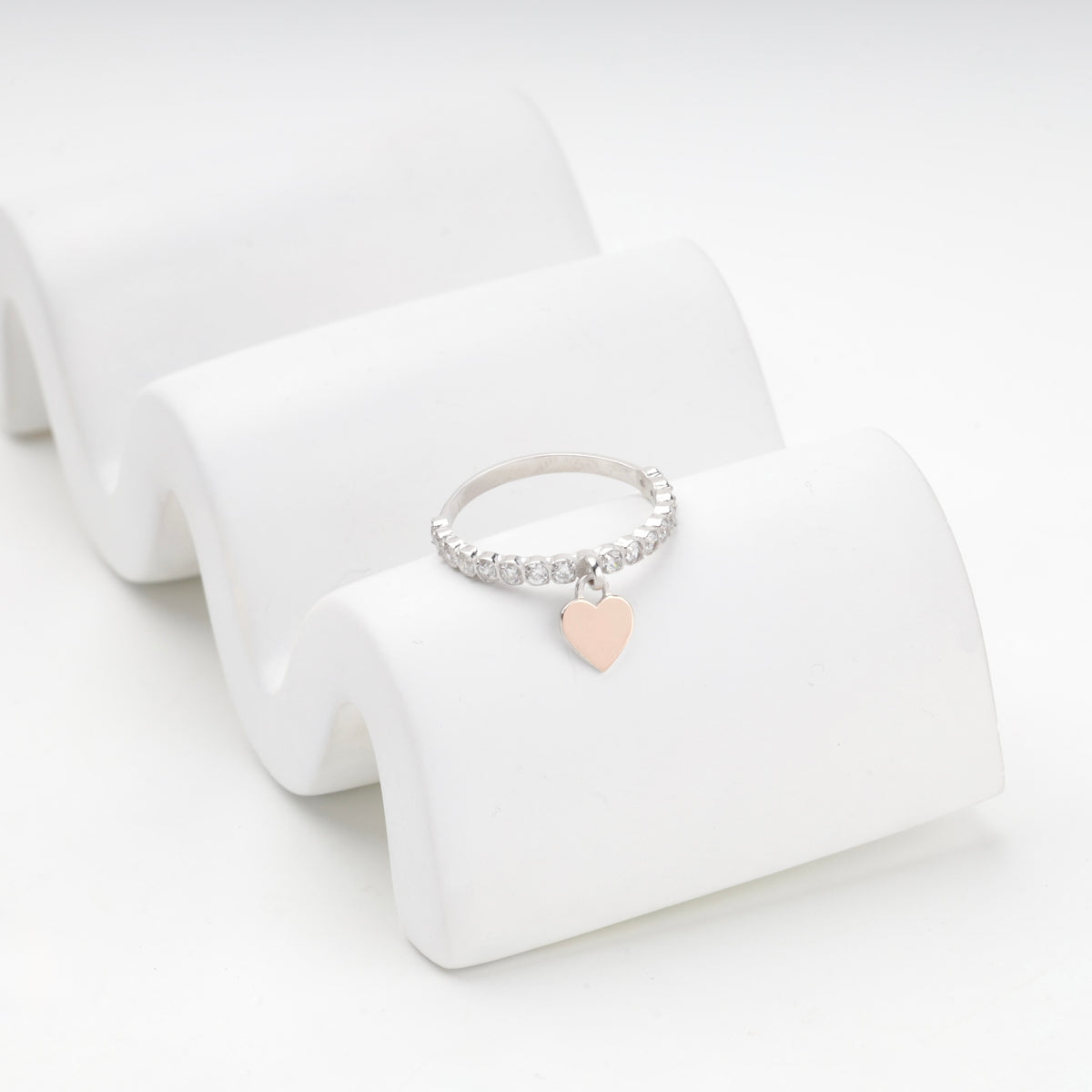 Heart charm ring in silver 925 resting on a curved white stand