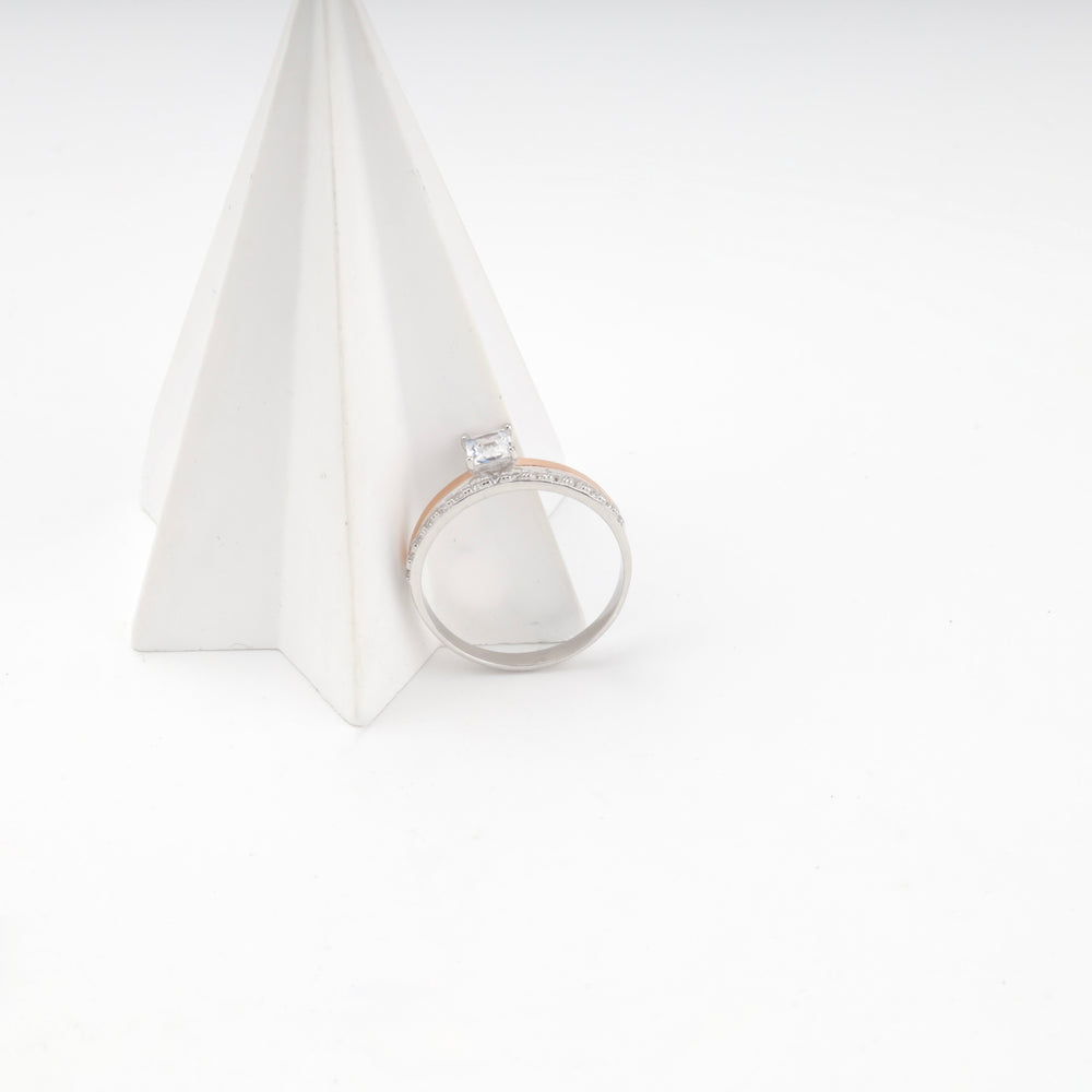 Two-tone silver and rose gold ring resting against a white geometric prop