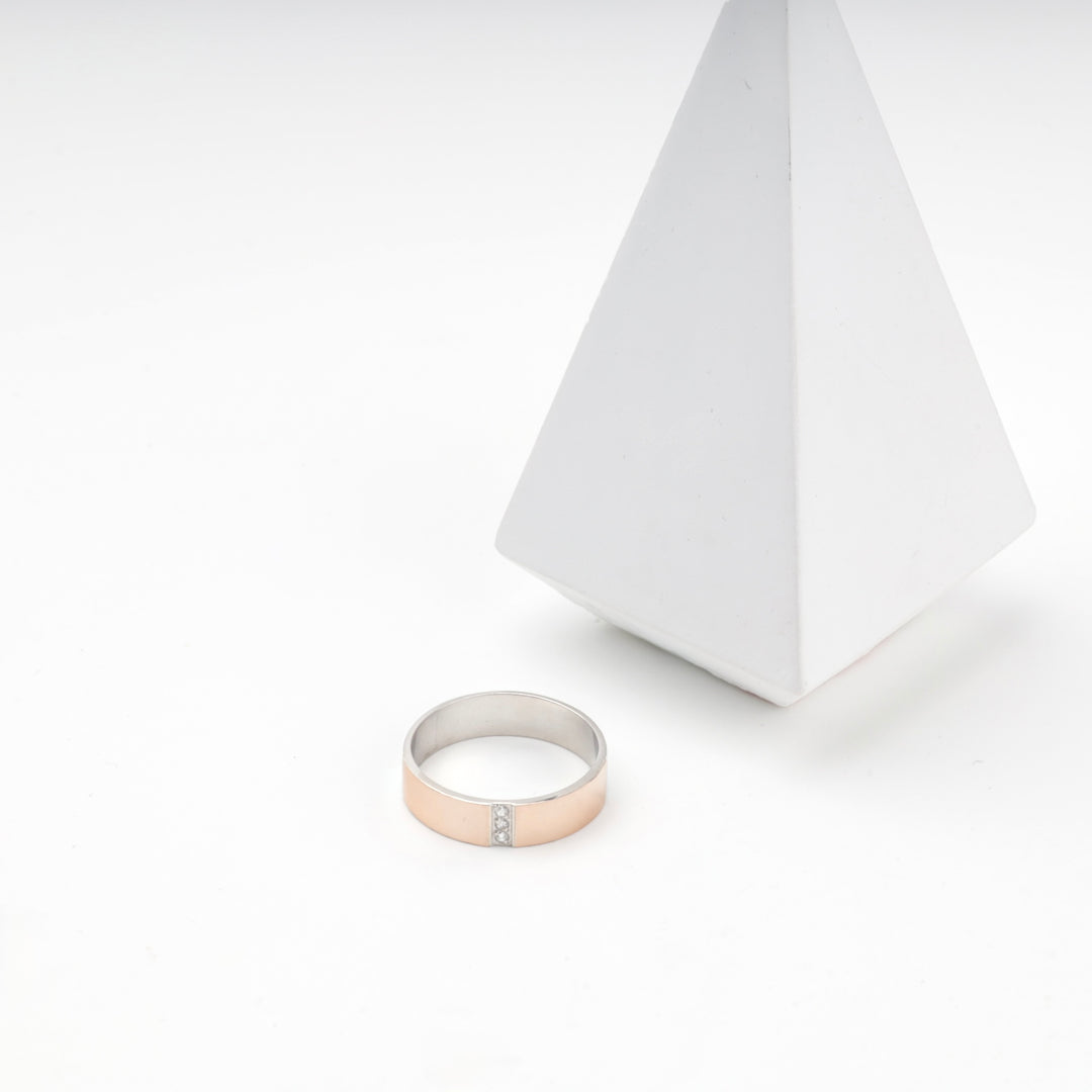 Silver 925 ring with rose gold half standing upright on a white surface