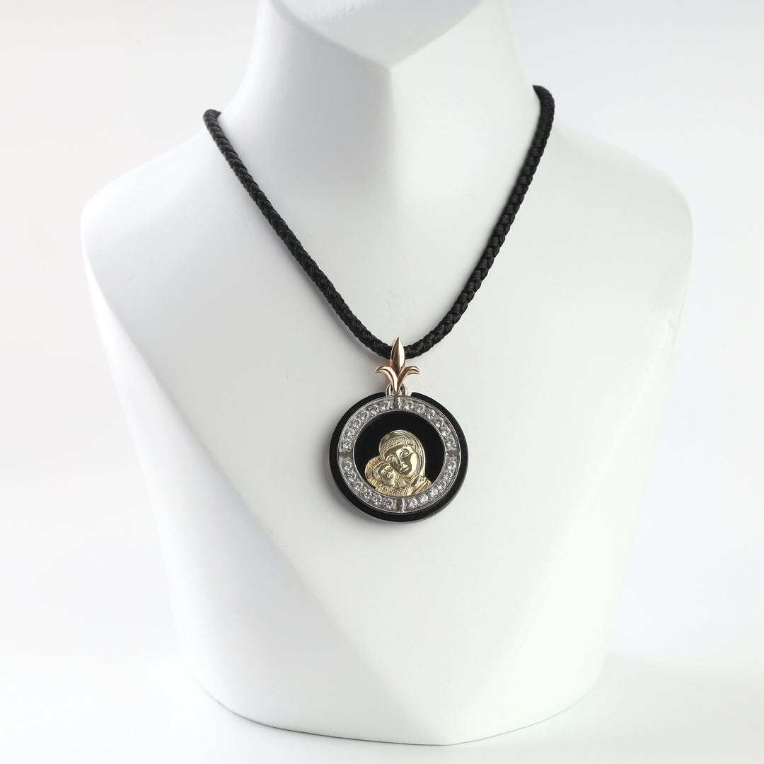 Gold Mother of God and Child pendant with black onyx and cubic zirconia halo on a black cord