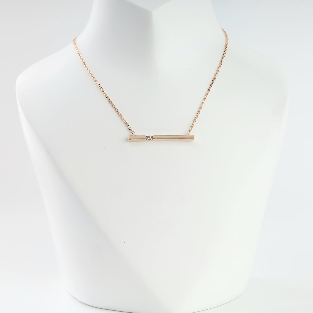 14K rose gold bar necklace with cubic zirconia on a display bust