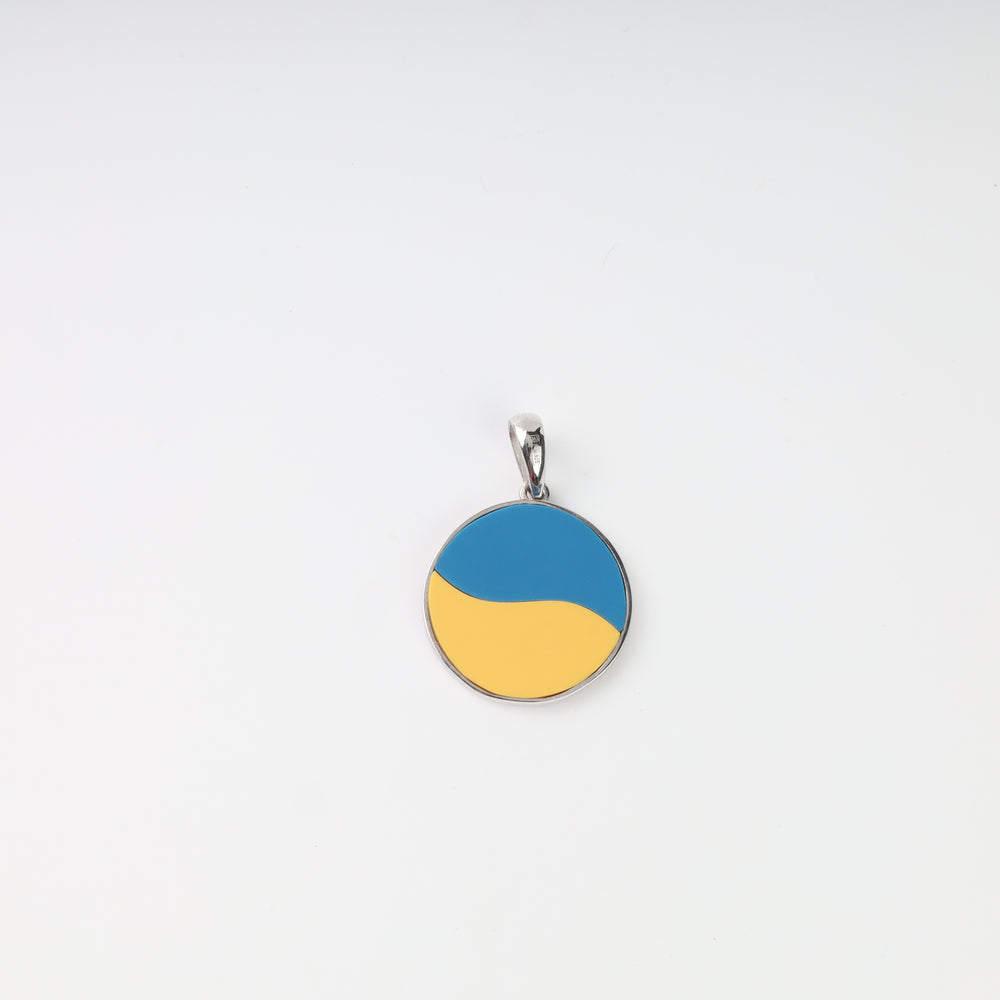 Reverse of blue-and-yellow round silver pendant with flowing color design