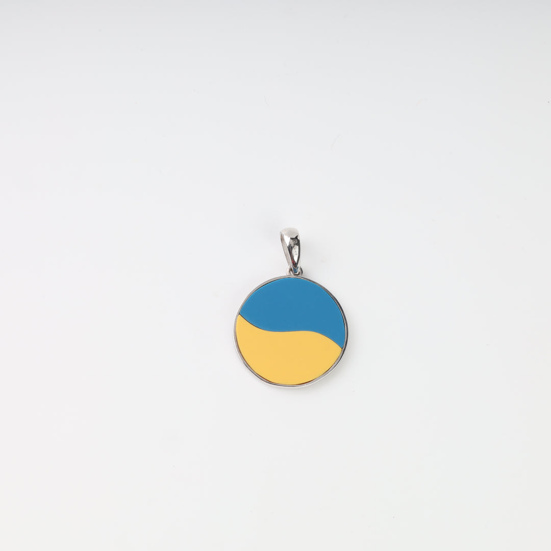 Reverse of blue-and-yellow round silver pendant with flowing color design