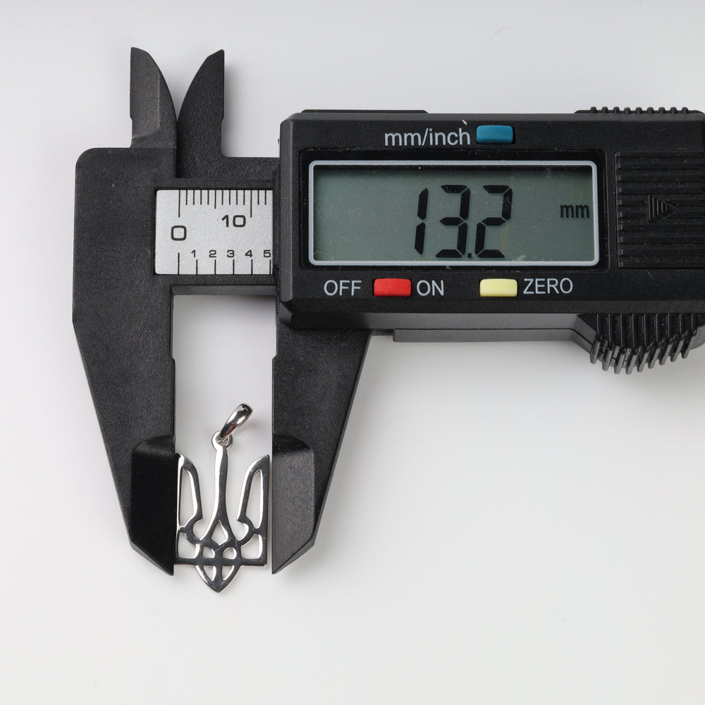 Caliper measuring the silver Tryzub pendant width at 13.2 mm