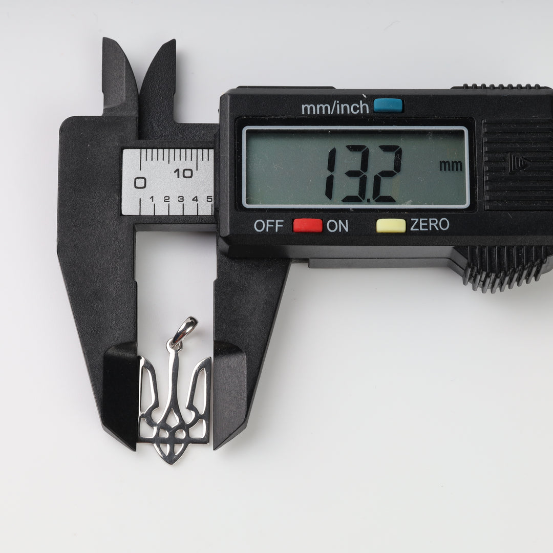 Caliper measuring the silver Tryzub pendant width at 13.2 mm