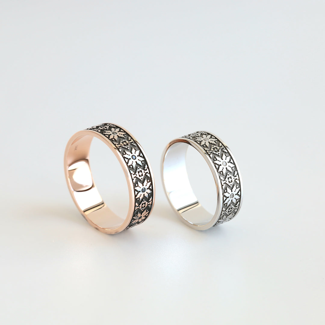 White and rose gold Ukrainian vyshyvanka wedding bands standing upright