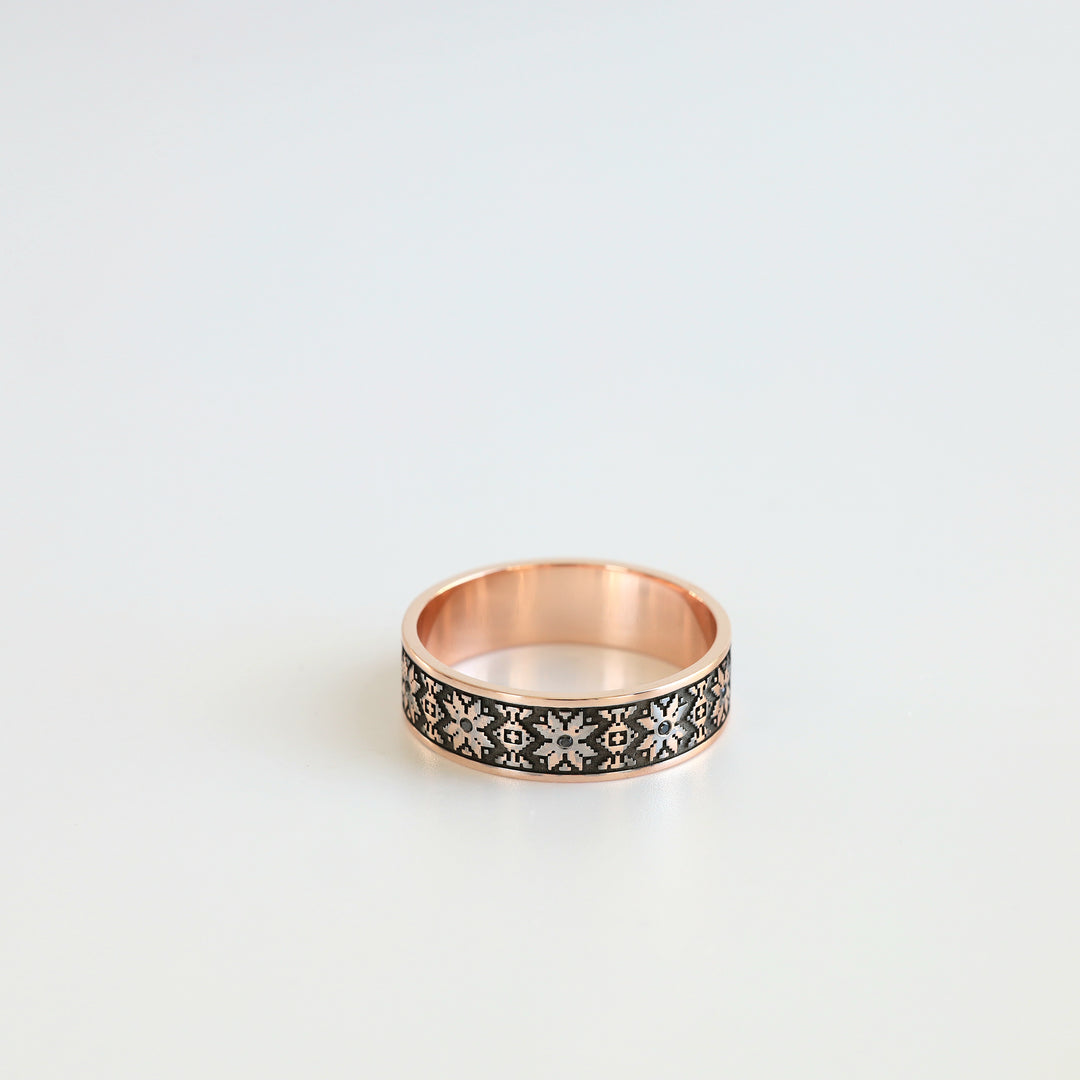 Rose gold vyshyvanka wedding ring, front view of the eight-pointed star pattern with black diamonds