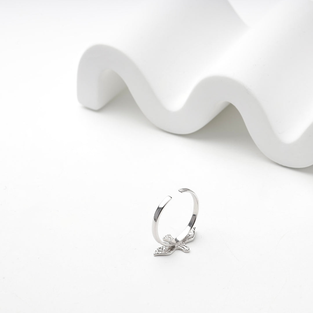 Adjustable silver bird ring in front of a white wave display