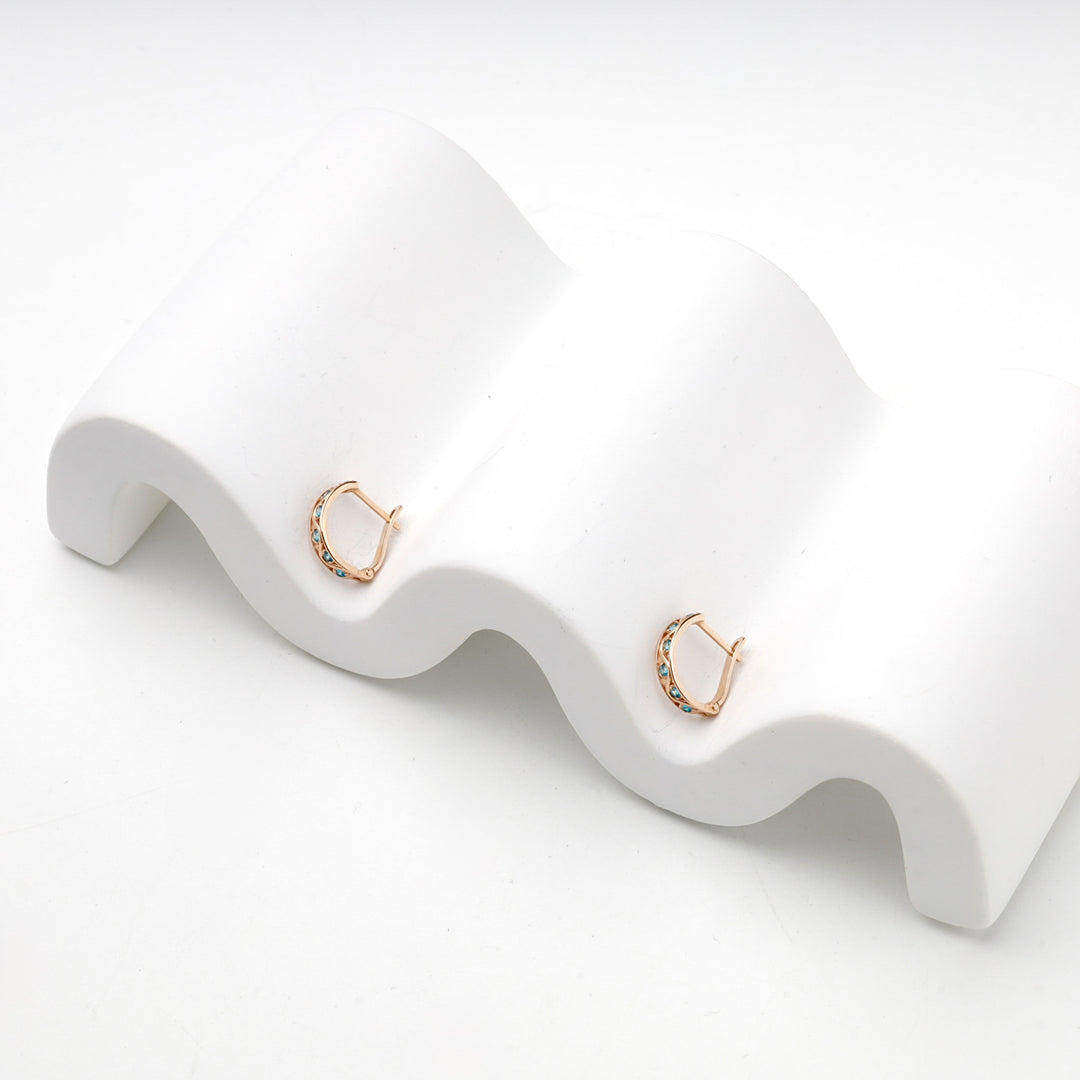 Pair of rose gold blue cubic zirconia hoop earrings, studio view