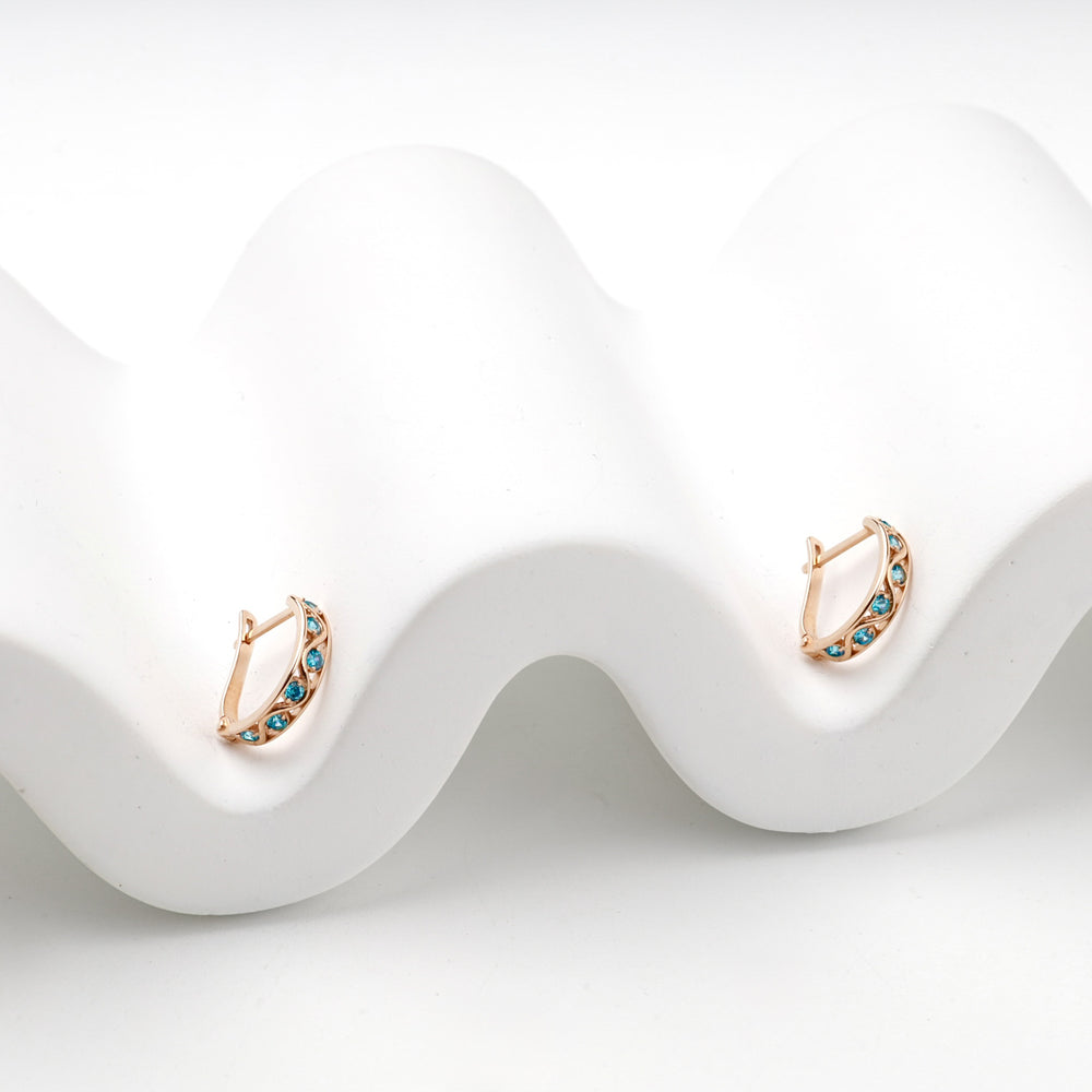 Rose gold latch-back hoop earrings with blue stones, angled view