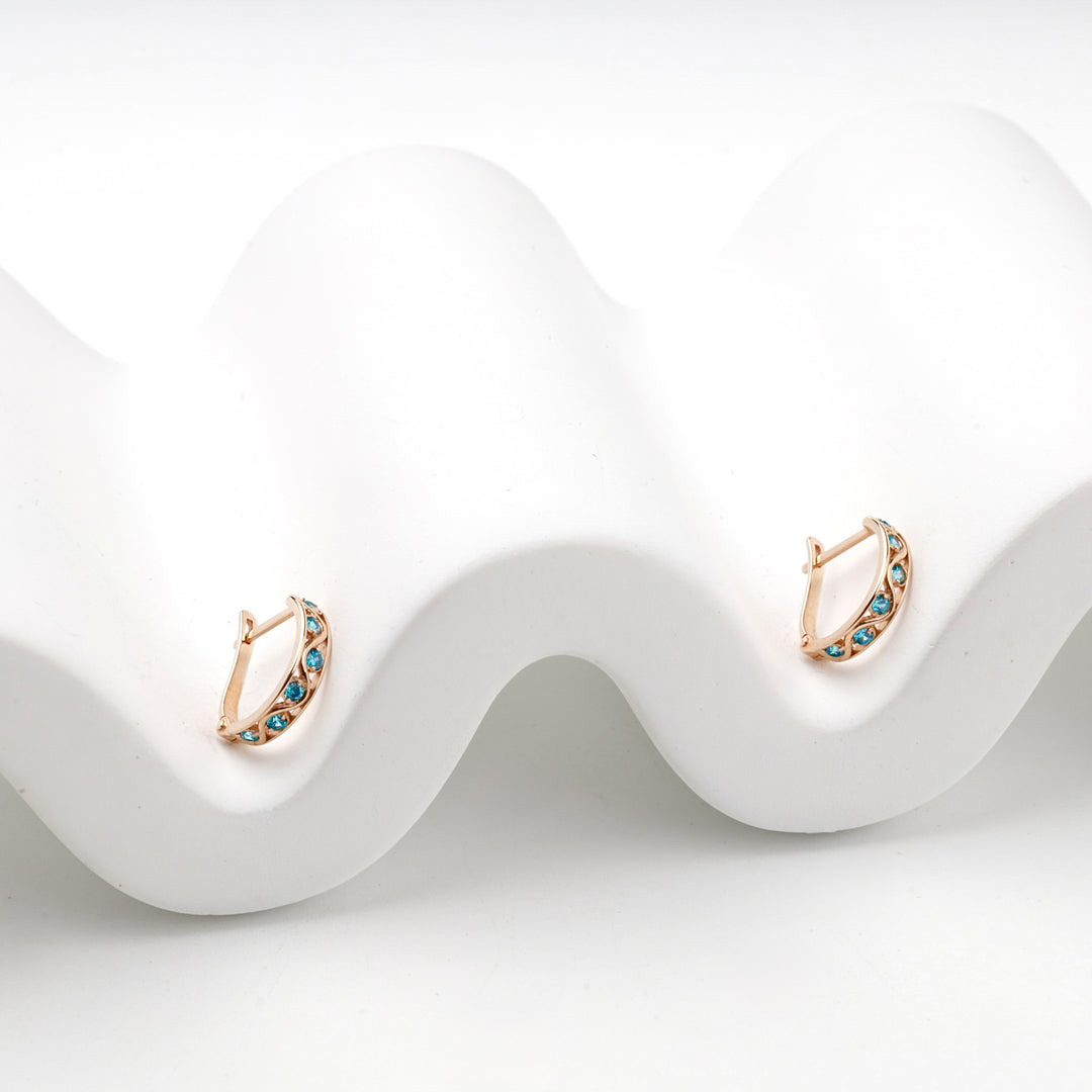 Rose gold latch-back hoop earrings with blue stones, angled view