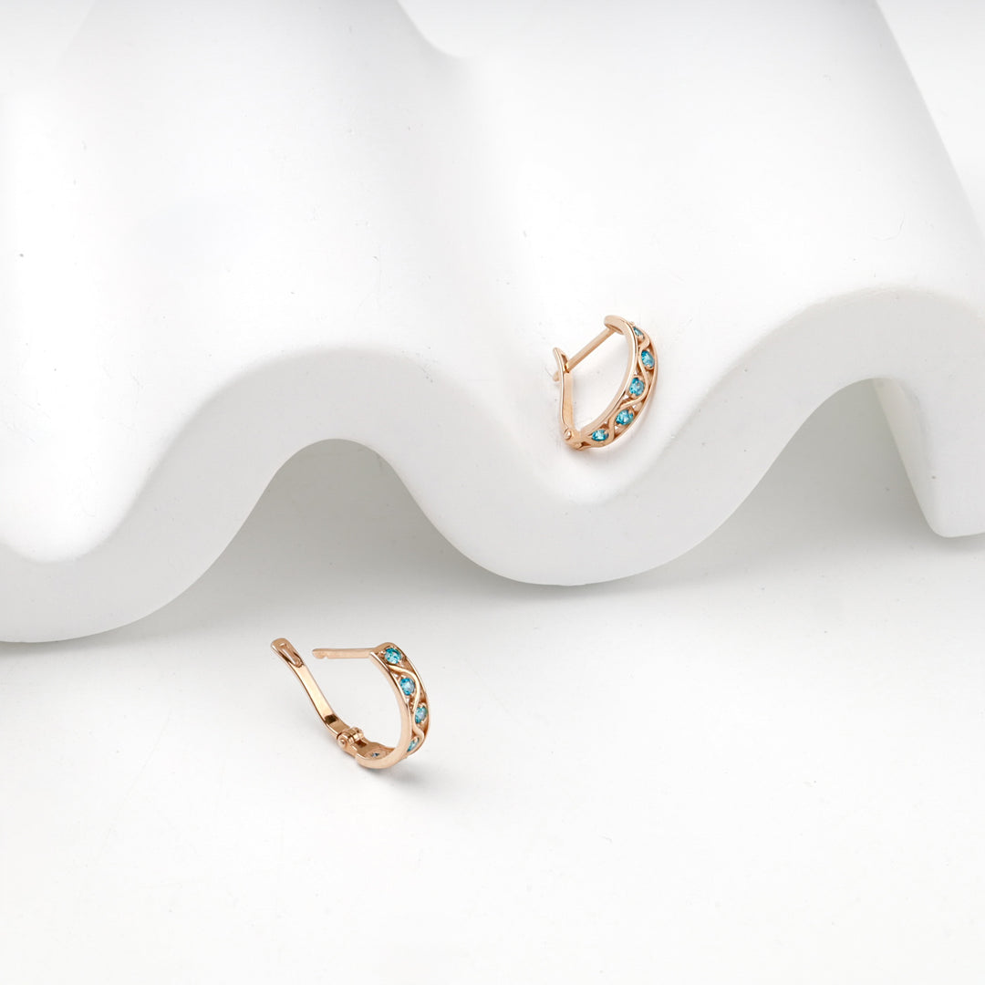 Rose gold hoop earrings with blue cubic zirconia, overhead view